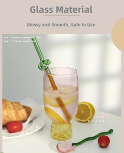 Close-up of pink glass cup with yellow base, green spiral straw, and lemon drink