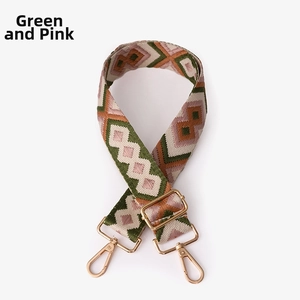 Close-up of ethnic geometric pattern wide strap in green and pink with gold metal buckles