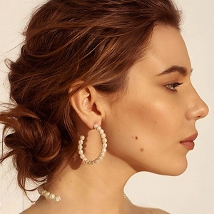 Eleganti orecchini a cerchio a C con perle tonde lucide su una modella