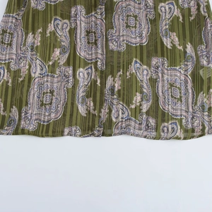 Detailed macro view of green paisley print on vertical pleated light fabric texture