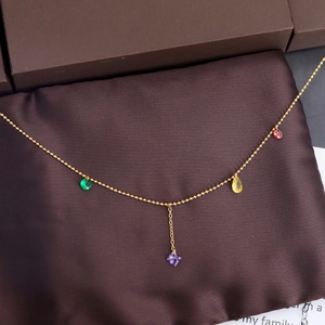 Luxurious gold bead chain necklace with multi-color gemstone pendants on silk background