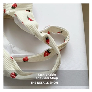 Close-up of corduroy shoulder strap with red strawberry pattern and white fabric lining