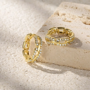 Macro detail of gold chain link earrings with micro-pave white zircon inlay on stone