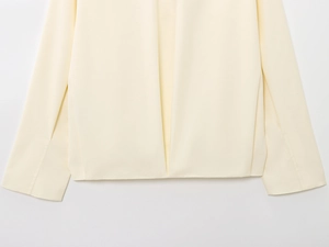 Detailed close-up of smooth cream-white bomber jacket hem and high-quality fabric texture
