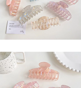 Flat lay of iridescent hair claws in various colors with artistic decor on white surface