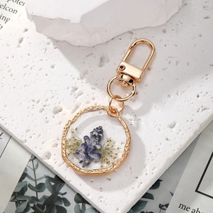 Chic golden keychain featuring a resin pendant with dried purple and white flowers