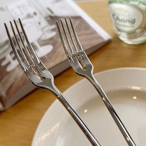 Close-up of polished stainless steel dessert forks on a wooden table with soft lighting