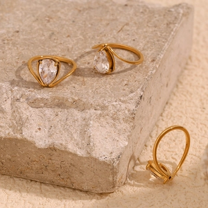 Close-up of 18K gold plated teardrop white zircon rings on natural stone background