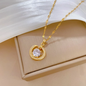 Elegant gold titanium necklace with a round zircon pendant on a beige jewelry box