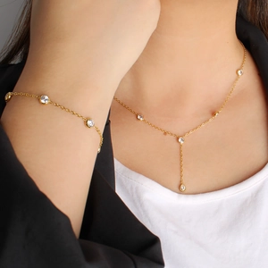 Golden stainless steel jewelry set with sparkling crystals featuring Y-necklace and bracelet