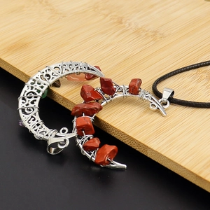 Macro view of silver wire wrapped moon pendant with red crystal stones on wood background