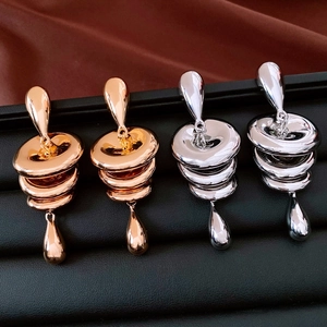 Makro-Detail von polierten Stufen-Ohrhängern in Silber und Roségold auf Leder