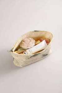 Detailed close-up of beige linen cosmetic bag with green floral embroidery and gold zipper