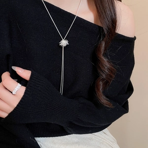 Elegant silver starburst zircon necklace and matching ring worn by a model on beige