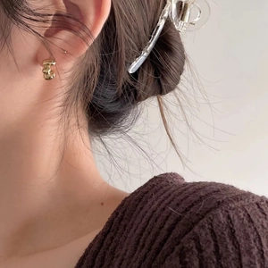 Close-up of golden layered wave earrings worn by a model with a minimalist chic style