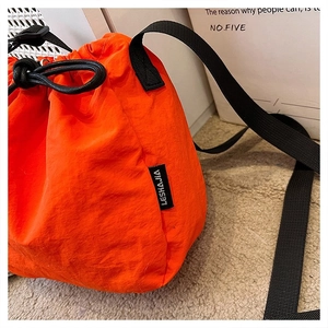 Detail of orange drawstring bucket bag showing water-resistant nylon fabric and texture