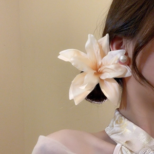 Detail of cream white fabric lily hair clip on model featuring delicate petal texture