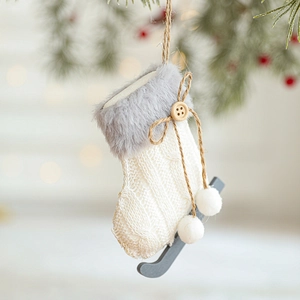 White knit plush ice skate Christmas stocking ornament hanging on a pine tree branch