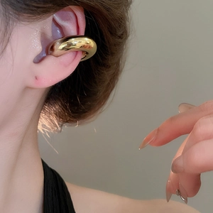 Gros plan d'une boucle d'oreille torsadée dorée sur un modèle avec détails texturés
