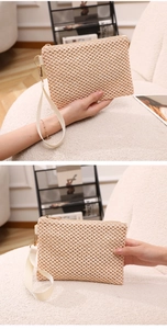 Detail of hand-woven straw wristlet bag with canvas strap and metal zipper closure