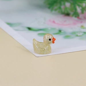 Macro shot of a mini yellow resin duck with golden glitter and smooth orange beak