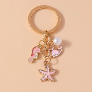 Detailed close-up of golden seahorse whale and starfish charms with a white pearl