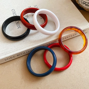 Close-up of minimalist resin bangles in multiple colors displayed on art books