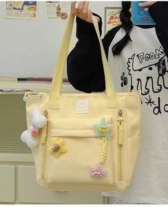 Detail of cream yellow nylon tote bag with colorful star charms and plush doll pendant