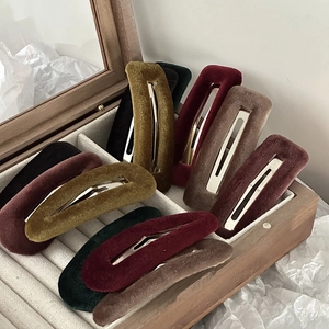 Detailed close-up of velvet BB hair clips in vintage autumn colors on a wooden tray