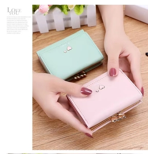 Detail of pink and mint green PU leather trifold wallets with heart shaped metal buckles