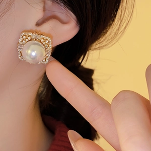 Close-up of vintage square earrings with large pearl and zircon studs on model