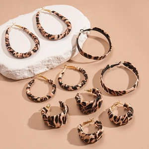5-pair set of leopard print hoop earrings in various sizes on a beige stone surface