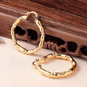 Orecchini a cerchio dorati con design a bambù lucido su un espositore vintage classico