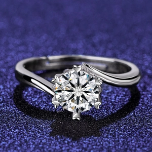 Macro shot of silver six-prong cubic zirconia ring with heart details on dark blue glitter