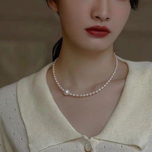 Elegant white freshwater pearl choker necklace with a large accent pearl on a female model