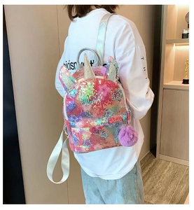 Detail of pink unicorn sequin backpack with star patterns and fuzzy pom-pom charm
