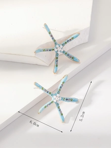 Detailed view of light blue starfish earrings with pearls and colorful rhinestones