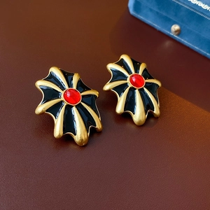 Dettaglio di orecchini vintage con pietra ovale rossa e smalto nero su fondo in pelle