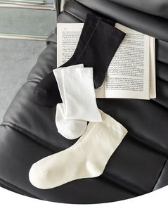 Detailed shot of black, white, and beige cotton socks resting on an open book