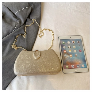 Macro shot of gold evening bag with textured finish, chain strap, and rhinestone buckle