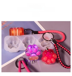 Detail view of cat paw silicone mold with resin charms and braided leather keychains