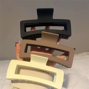 Detail view of large matte resin square hair claws in black, brown, and cream colors