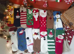 Flat lay of colorful coral fleece Christmas socks with festive elk and Santa Claus patterns