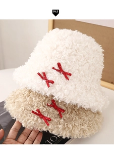 Détail de bobs en peluche blanc et beige avec des nœuds rouges à pois blancs