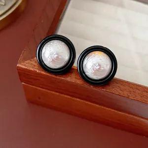 Minimalist round stud earrings in black and white finish displayed on a walnut wooden box