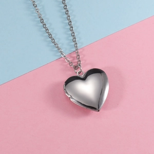 Detailed view of silver heart-shaped photo locket necklace on pastel background