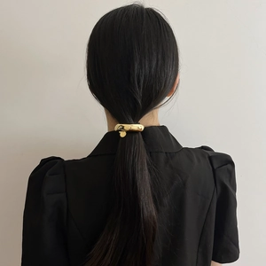 Detail of golden minimalist geometric metal hair ring on ponytail with small charm