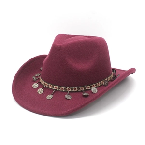 Detail of burgundy cowboy hat with ethnic braided band and vintage silver metal pendants