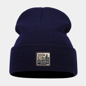 Detailed view of dark blue knit beanie featuring a vintage Denim Supplies logo patch