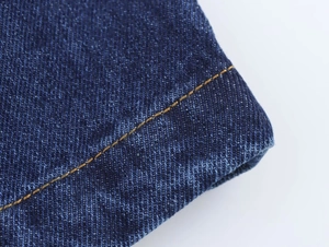Gros plan sur le tissu denim bleu foncé avec coutures orange et texture sergée